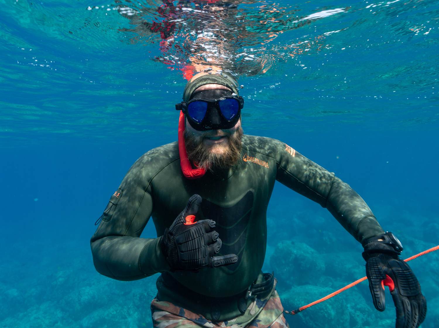 Freediver shaka just below the surface, Kona