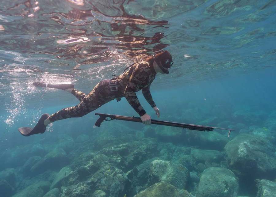Private guide and guest freediving with speargun off Kona